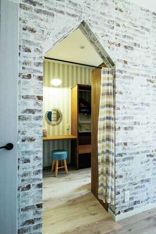 シックな寝室はレンガ調のクロスを用いた。ウォークインクローゼットの入り口は、三角屋根のような開口部に。入るとすぐの場所にドレッサーコーナーを設置。身支度動線も便利に