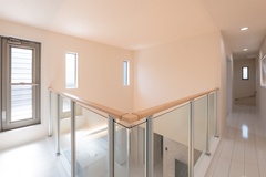 明るい光が差し込む廊下。手すりにはガラスを使用し、視覚的に広がりを感じさせるデザインとなっている。
