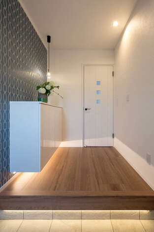 玄関は、白をベースに清潔感のある印象に。アクセントクロスやペンダント照明、間接照明を加えてモダンに演出した