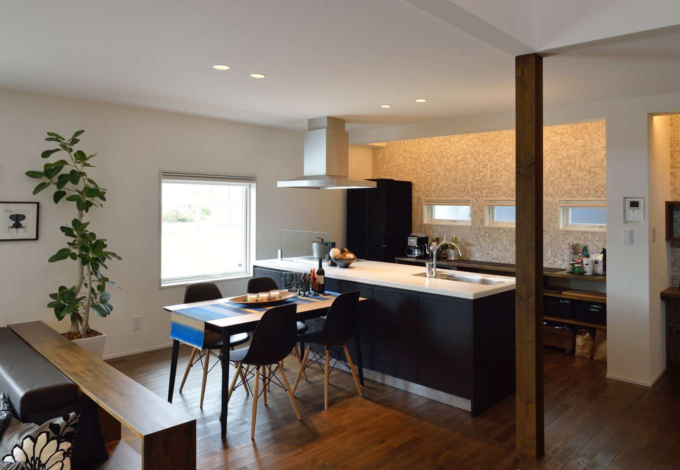 SEIEN ARCHITECT【デザイン住宅、建築家、インテリア】南側に面した明るいダイニングキッチン。ステップダウンリビングのウォルナットの壁とは対照的に、キッチンの壁面はタイル貼りにしてモダンなイメージを演出