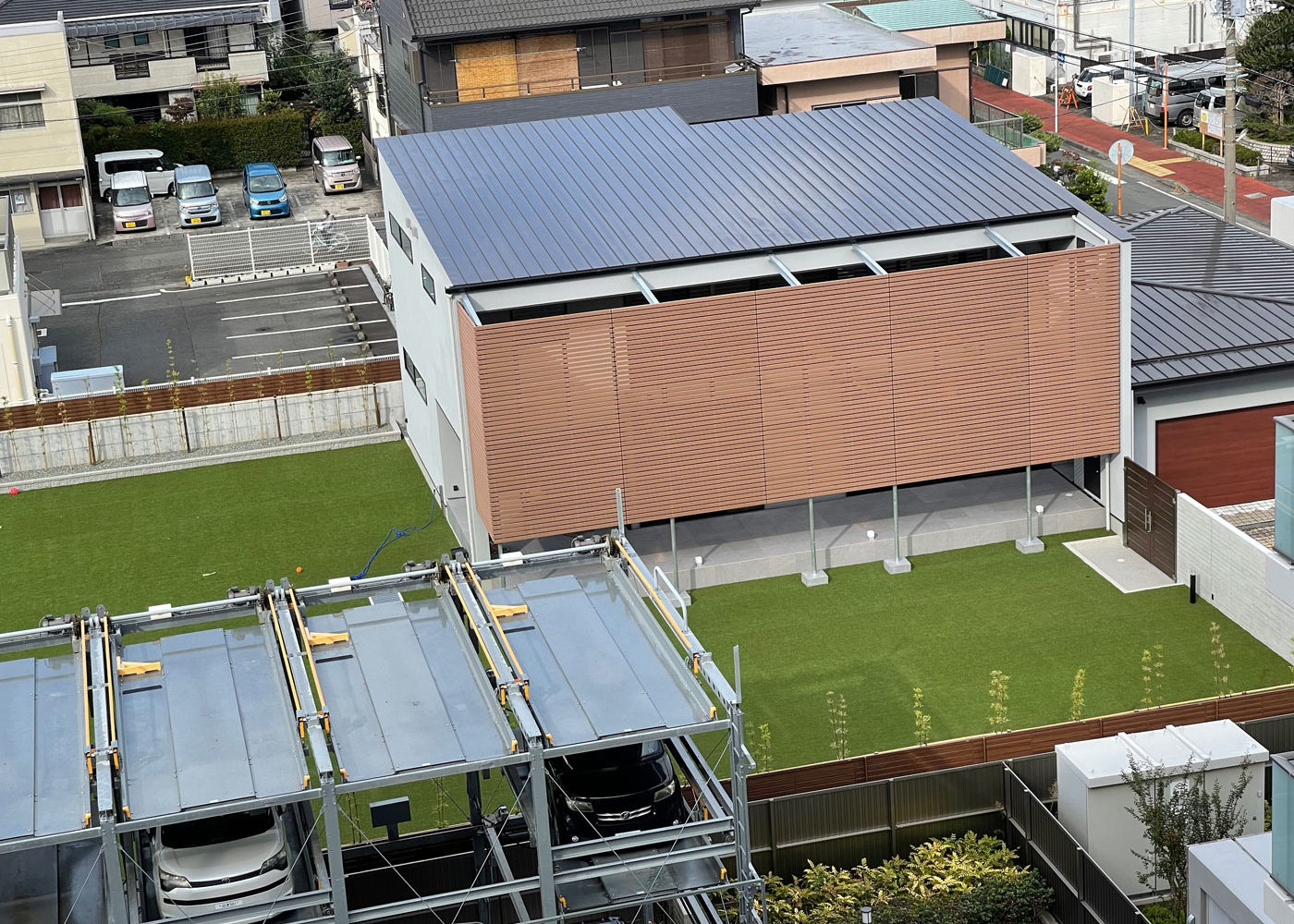 TENアーキテクツ 一級建築士事務所【デザイン住宅、高級住宅、建築家】駅から近い、街中の広大な敷地に完成したA邸。最も日当たりがいい南側に高層アパートが立っているため、巨大なルーバーを設置して外からの視線をカット。プライバシーを守りながら、たっぷりの光と風を取り込み、開放感も叶えている
