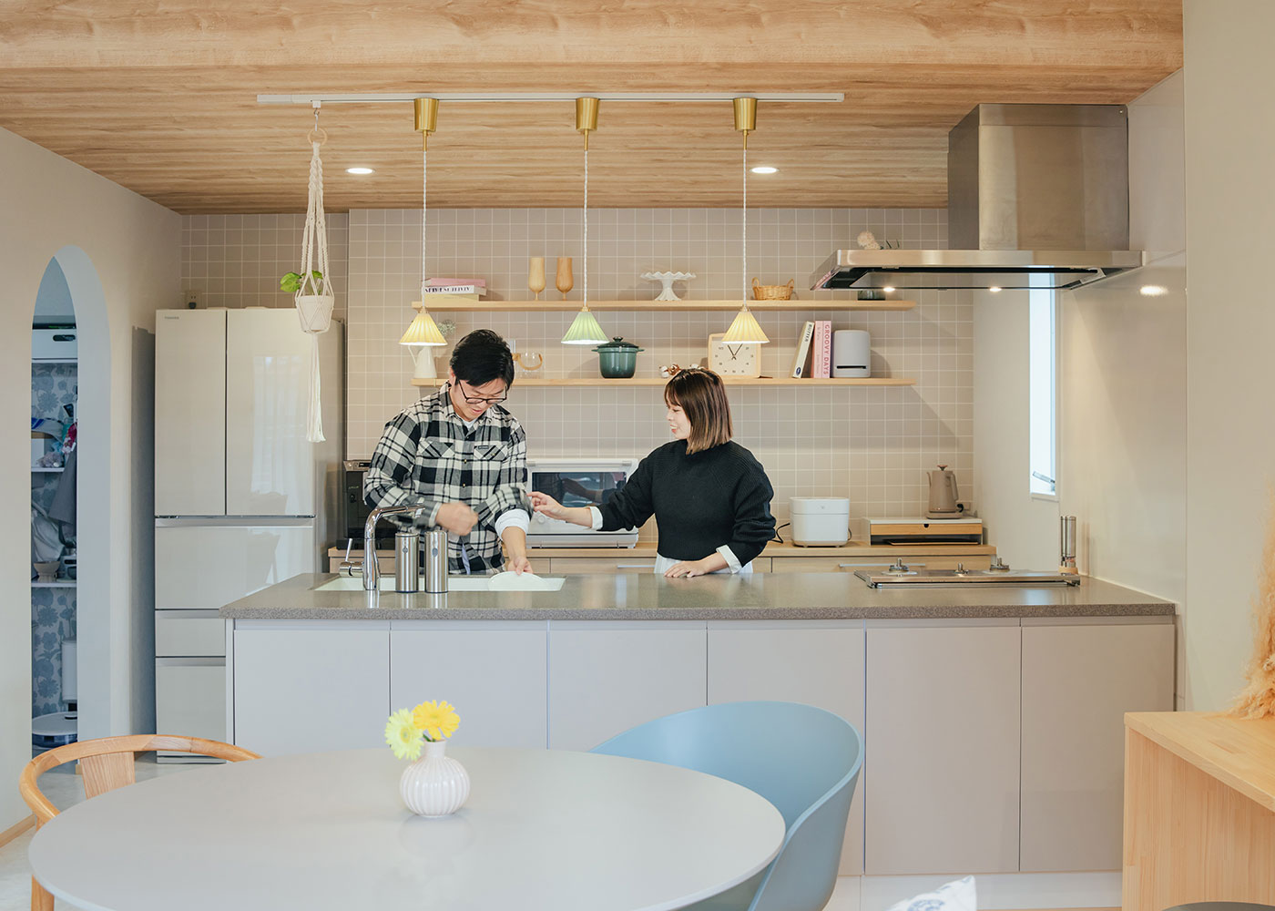 フジモクの家（富士木材）【趣味、自然素材、間取り】折り下げ天井のキッチンは、ライトグレイッシュの配色と木目のやさしさが融合し、居心地のいい場所に。お気に入りのペンダントライトや雑貨もマッチする。左手のアーチの先はパントリーに
