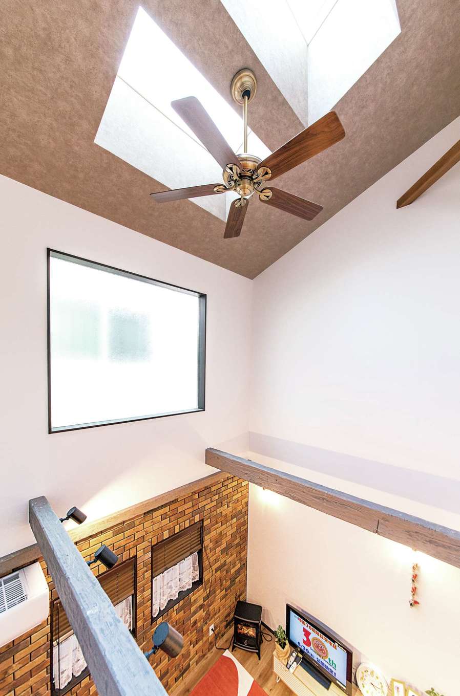 三和建設【子育て、収納力、自然素材】吹き抜けの壁の上部には大きな窓が。さらに天井にはトップライトを設け、採光は充分。天井のシーリングファンが家中の空気を循環させるので、冷暖房効率もアップ