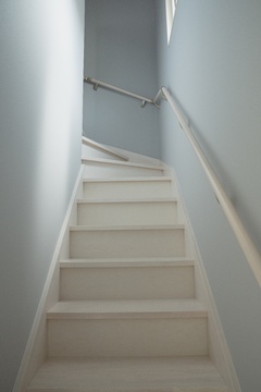 シンプルで機能的な階段。ホワイトを基調としたデザインが清潔感を演出し、安全性を考慮した手すりが設置されている。
