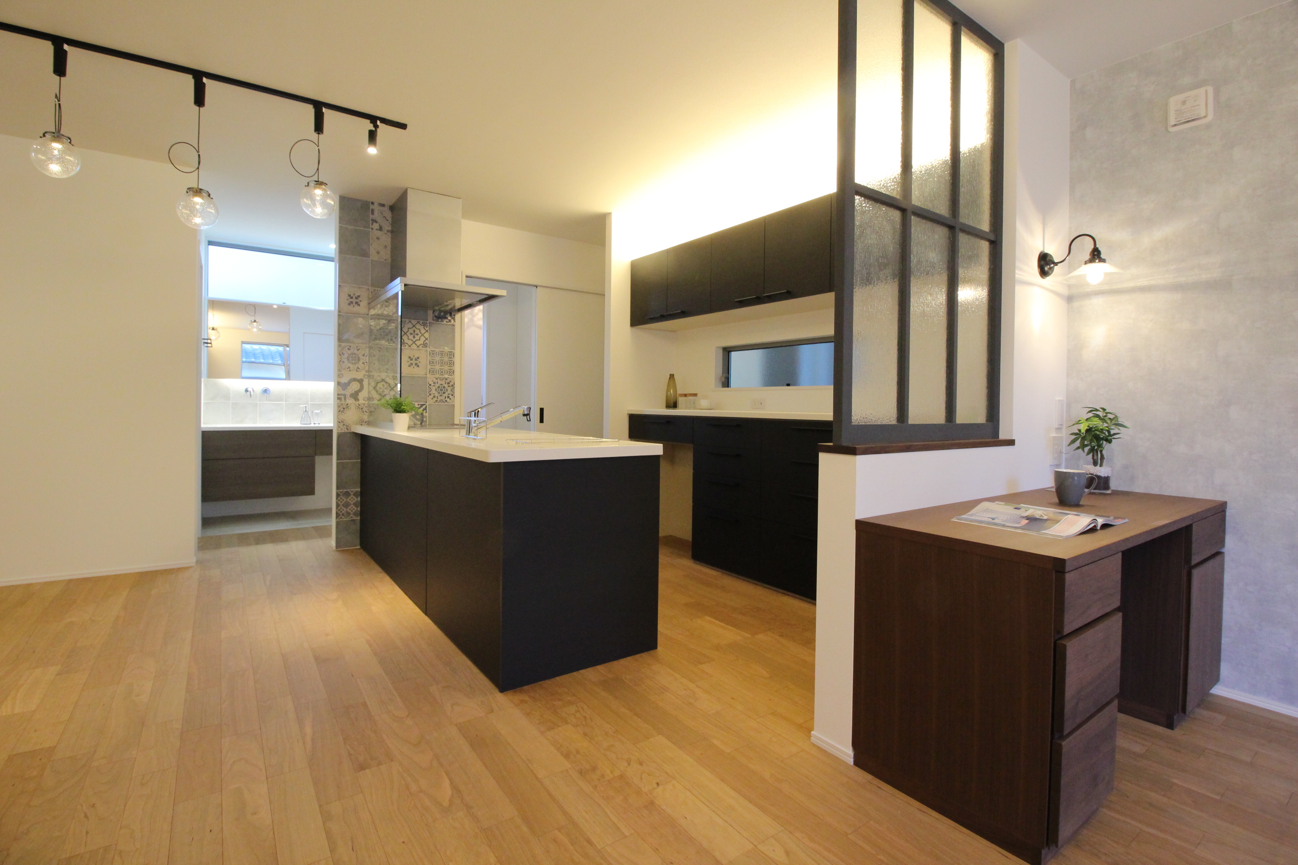 小野田産業～designers house project～｜広々としたキッチン空間に、モダンなデザインが施されている。カウンターを中心に作業スペースを効率的に配置し、アースカラーが落ち着いた雰囲気を演出している。