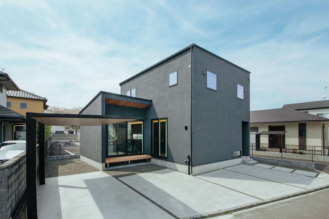 住家 JYUKA【デザイン住宅、省エネ、間取り】シャープなフォルムと塗り壁の表情が確かな存在感と住まい手のセンスを感じさせる。玄関とデッキ回りには無垢を張り、あたたかな印象をプラス