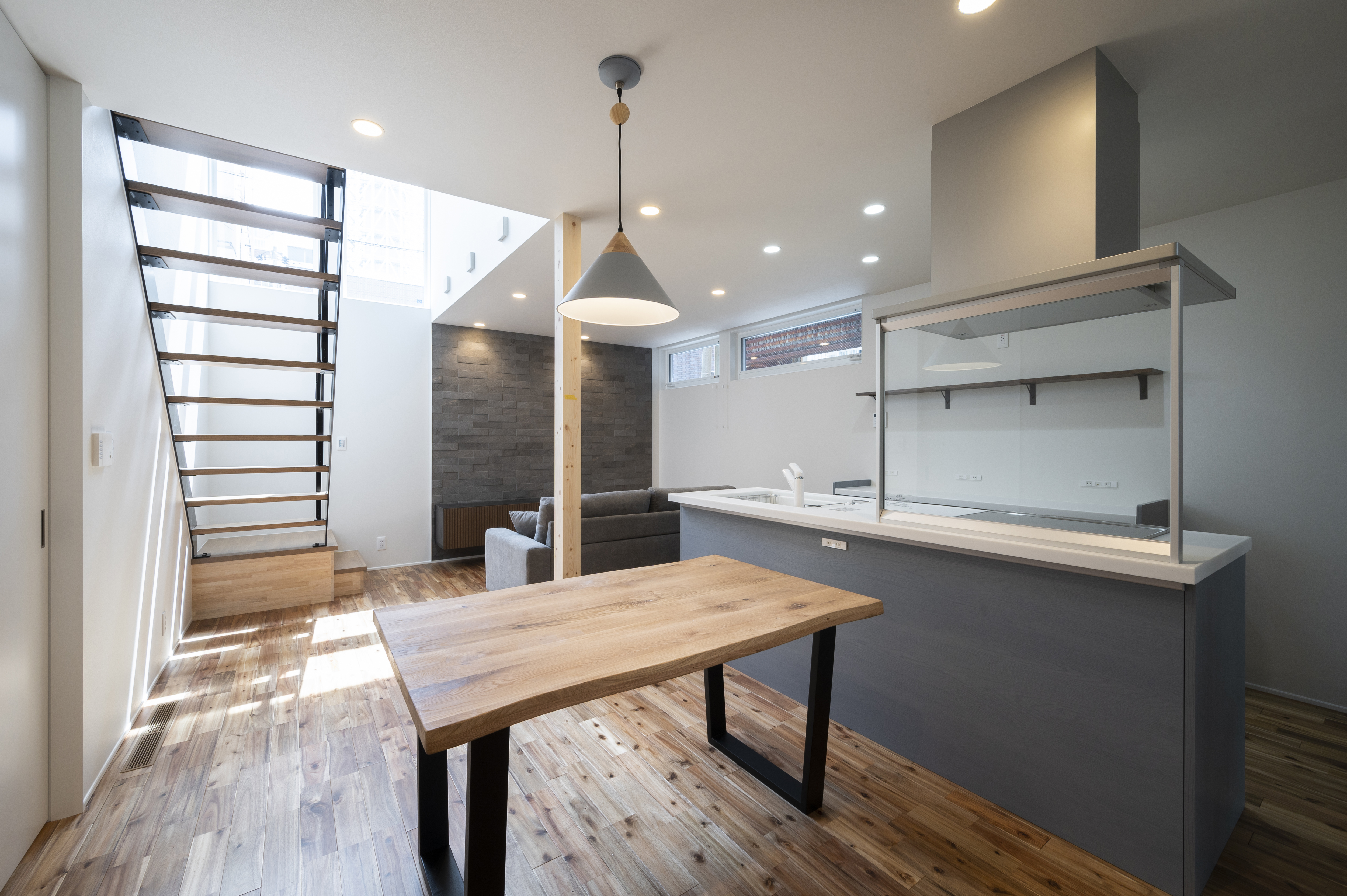 オネストアーク｜木目調のフローリングが温かい印象のダイニングスペース。広々とした空間には、大きな窓から自然光が差し込み、明るく開放的である。モダンな照明がアクセントとなっている。