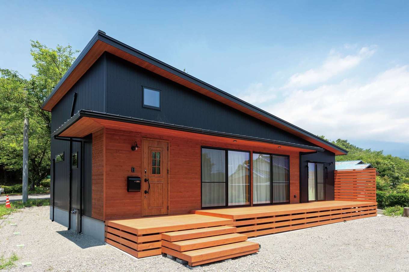 フジモクの家（富士木材）【デザイン住宅、自然素材、平屋】富士山と桜並木を背景に、山小屋風の平屋が美しく映える。思わず二度見してしまうほど美しい、別荘の山小屋のような外観。深い軒が夏の直射日光を遮り、冬は室内の奥まで光を届ける。庭とリビングをつなぐ大きなウッドデッキはアウトドアリビングとして大活躍