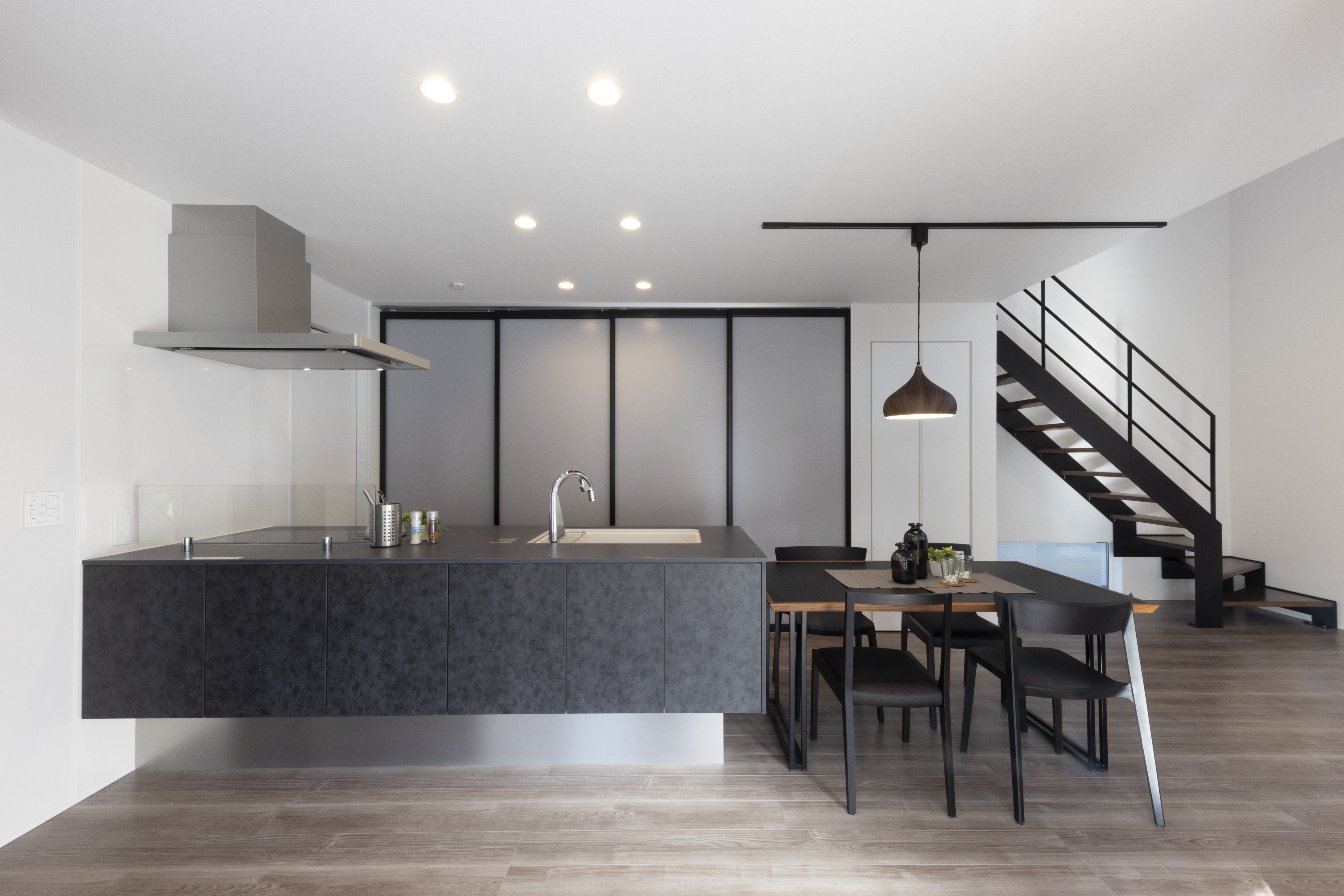 フェスティナ・レンテ｜モダンなデザインのLDKスペース。シンプルなダイニングテーブルとキッチンが空間をスッキリと見せ、階段がスタイリッシュなアクセントとなっている。