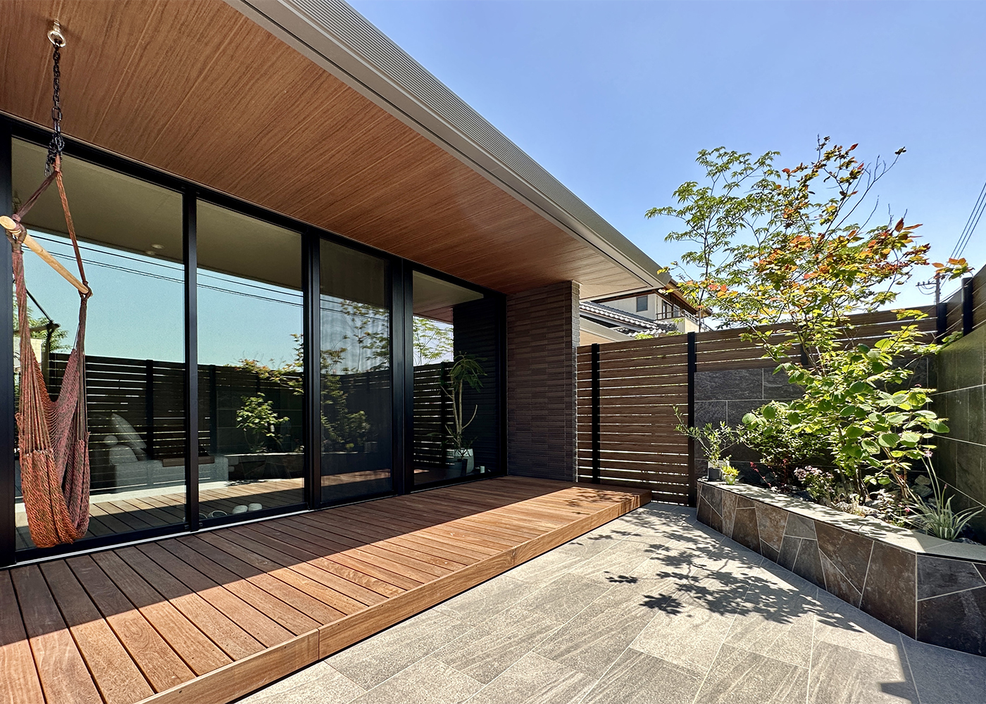 積水ハウス 豊橋支店【デザイン住宅、子育て、平屋】デッキと庭の段差を少なくすることで、庭とのつながりを持たせ、より空間が広く感じられるように設計されている。家だけではなく、インテリアや外構も含め、敷地全体を設計するのが『積水ハウス』。設計する際は日当たりや風の通り具合、傾斜具合など敷地を読み取りベストなプランを提案をする