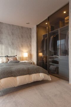 温かみのある照明と洗練されたデザインが特徴の寝室です。床から天井までの収納が備え付けられ、機能性と美しさを兼ね備えています。