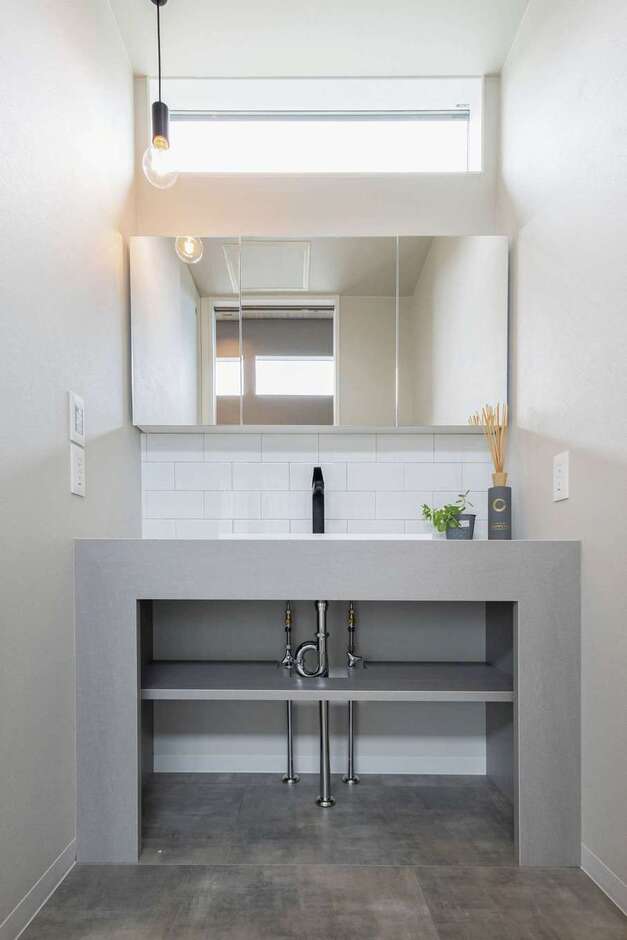 無機質でホテルライクなデザインに仕上げた洗面室。脱衣所と分けたことで、誰かが入浴中でも自由に使うことができる