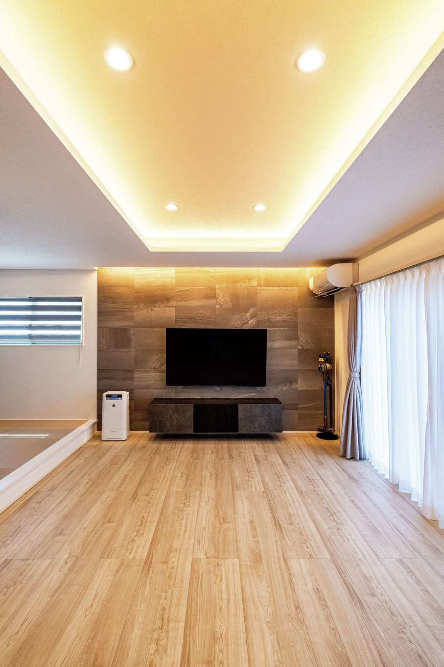 旭建設【子育て、収納力、間取り】折り上げ天井のほか、エコカラットのテレビボードにも間接照明を仕込み、素材感を強調して高級感を演出
