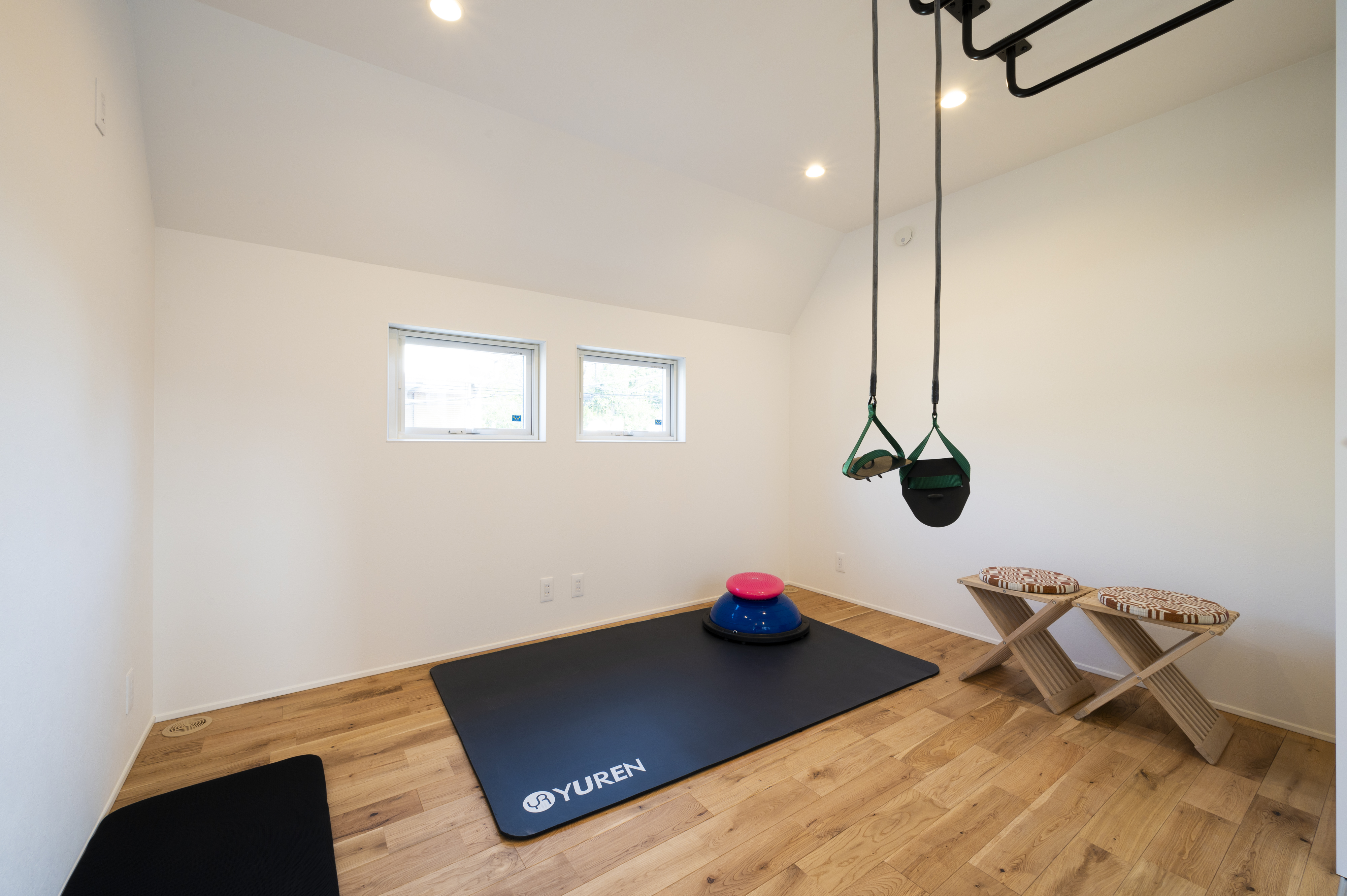 オネストアーク｜フローリングのジムスペース。トレーニング用のマットとツールが備えられ、日常的なエクササイズに適した空間である。コンパクトながらも機能的。