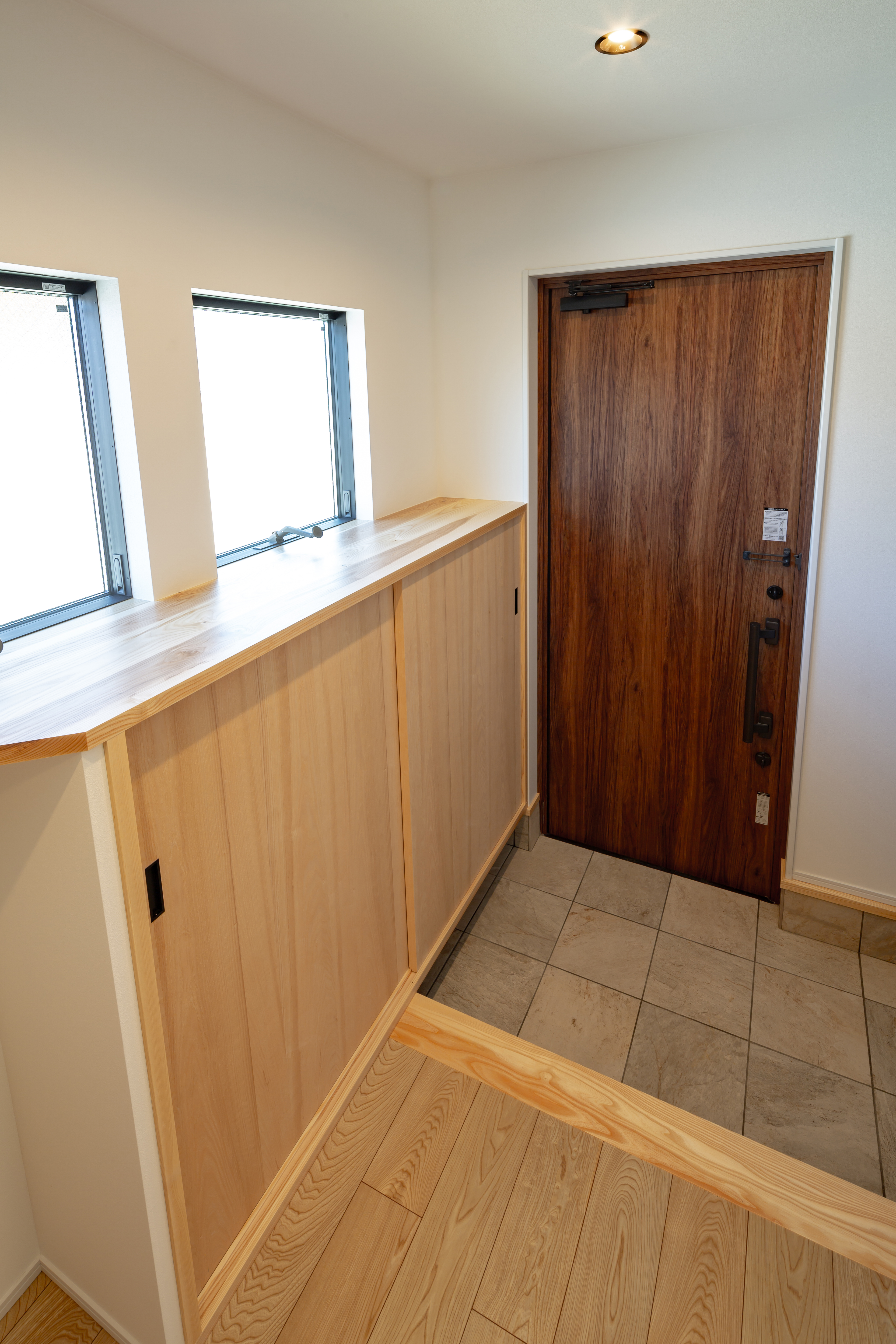 ムニカデザイン（まほろばホーム）｜玄関に下駄箱を設置しながら窓も取り入れることで、収納力と採光のバランスを絶妙に調整。機能性だけでなく、空間に開放感と温もりを与える工夫が施されることで、玄関がより心地よい場所へと