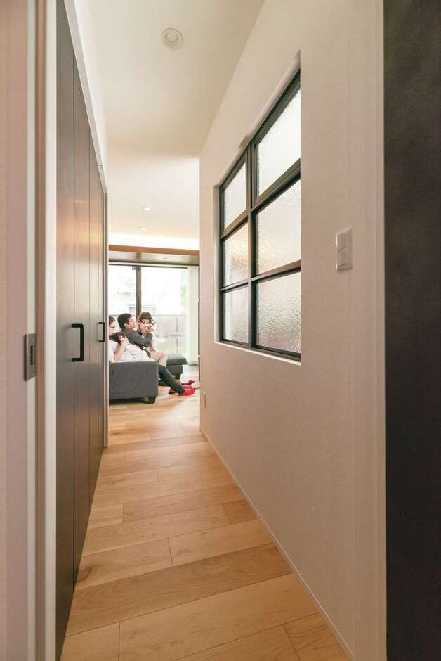 玄関からリビングへの廊下は、左側一面が収納スペース。建具はチャコールブラックで統一されている。右側の奥は、多目的に使えるフリースペース