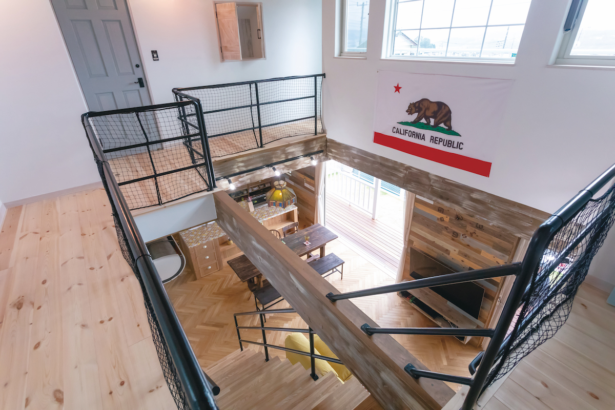 富士ホームズデザイン【子育て、自然素材、インテリア】カリフォルニア州旗がかかる吹き抜け。ネット（網）の無造作な手すりもインテリアにマッチ