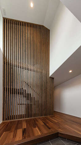 清々しさが漂う玄関ホール。天井まで届く格子が格段を緩やかに隠すと同時にインテリアの一部にもなっている