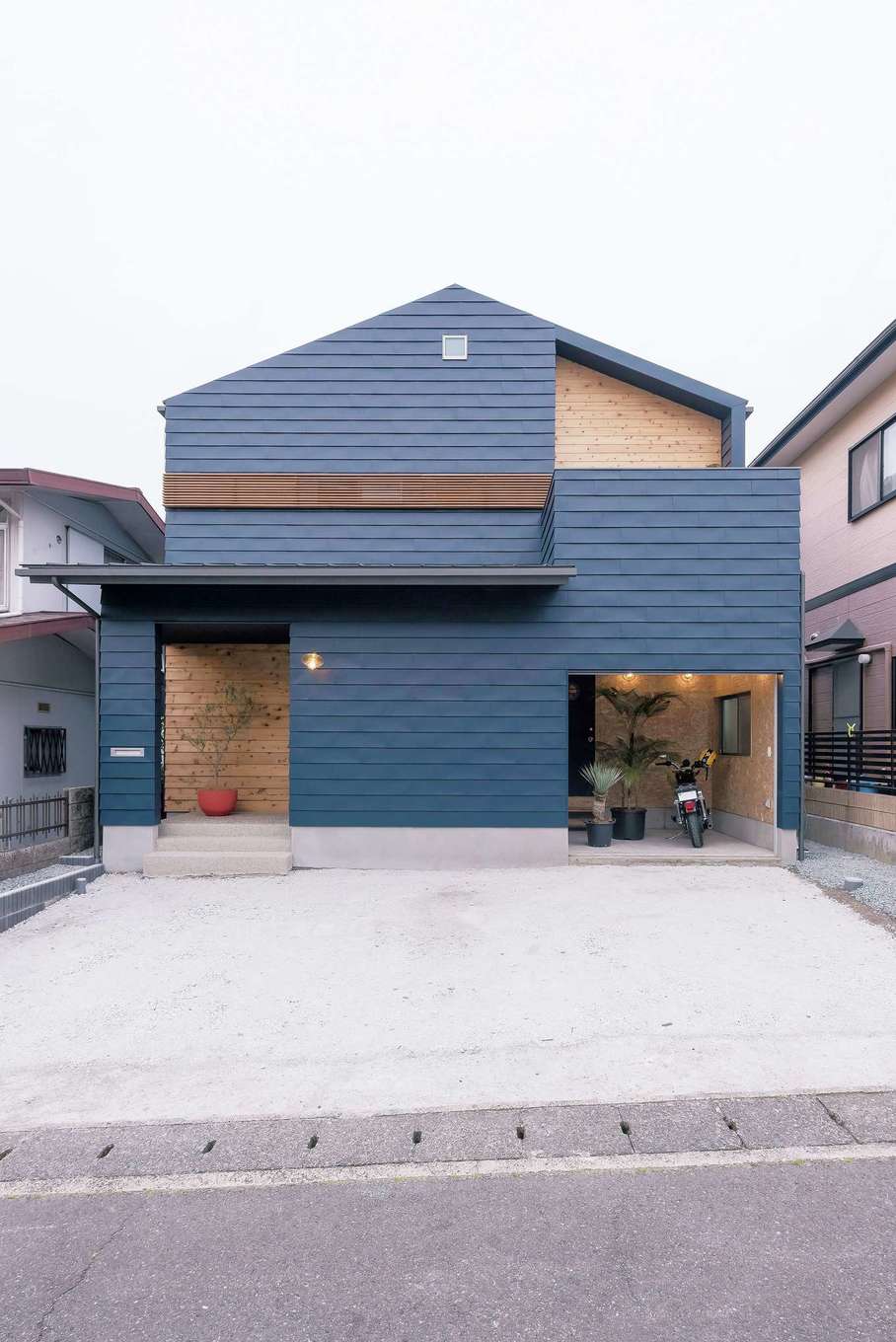 Hands Works（アオイ建築）【デザイン住宅、夫婦で暮らす、間取り】濃紺のガルバリウムをよろい張りにした、アメリカンテイストの外観。玄関ポーチと2階の一部はレッドシダーを用いてアクセントに。作業スペースや収納棚も確保したバイクガレージは、壁の下地材をそのままにして男前な空間に