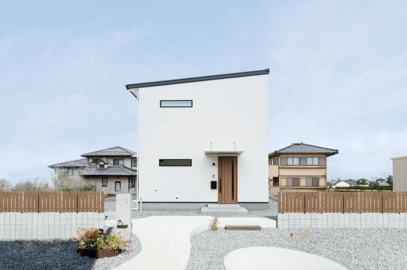 ひだまり工房【子育て、収納力、間取り】片流れ屋根と白い壁に、木調の玄関ドアがアクセントとなった可愛らしい外観。