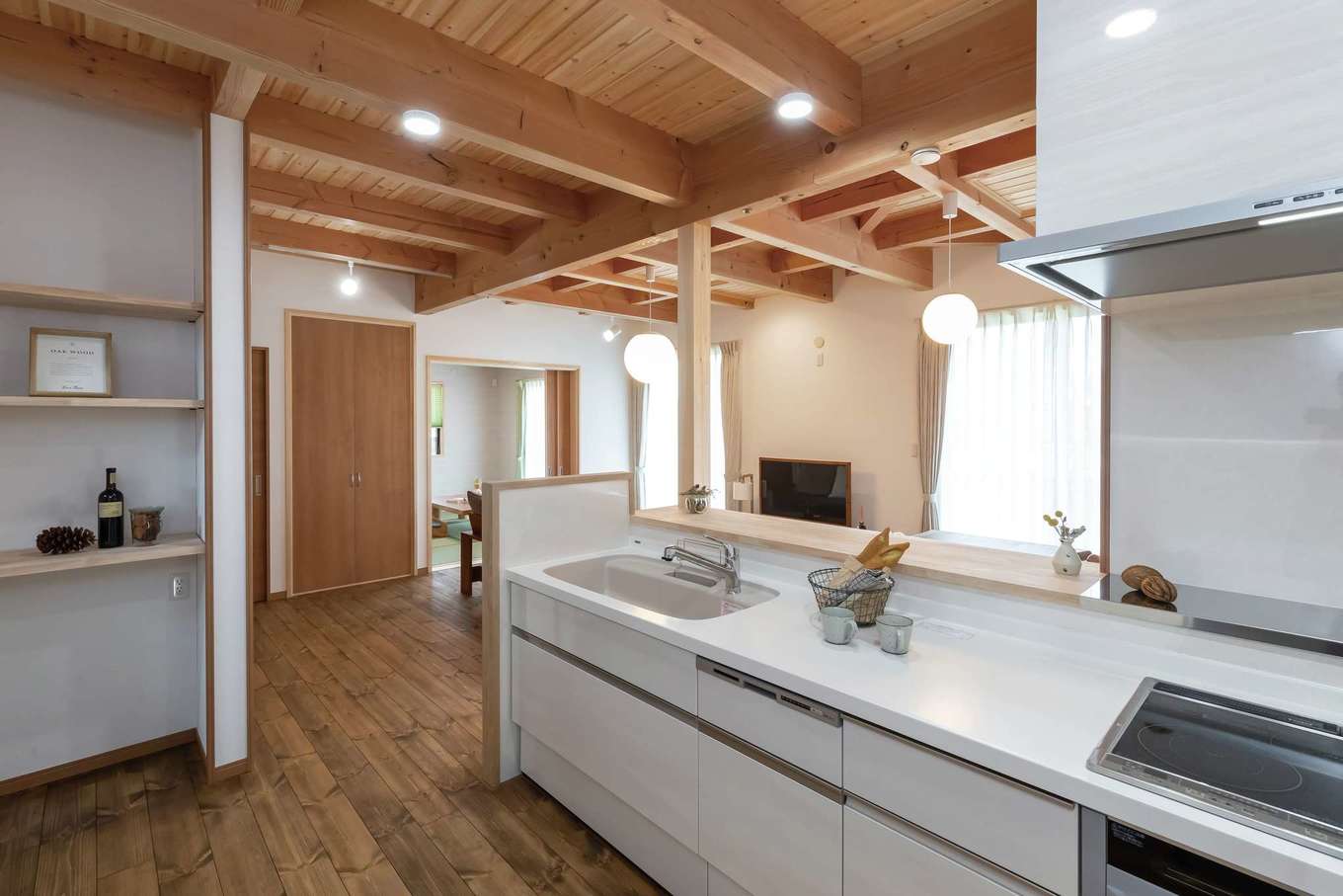 住まいるコーポレーション【デザイン住宅、和風、自然素材】白いシステムキッチンが天然木の素朴な風合いと調和して、ナチュラルで清潔感のある雰囲気に。キッチンに立つと、室内全体や外の庭まで見渡せる
