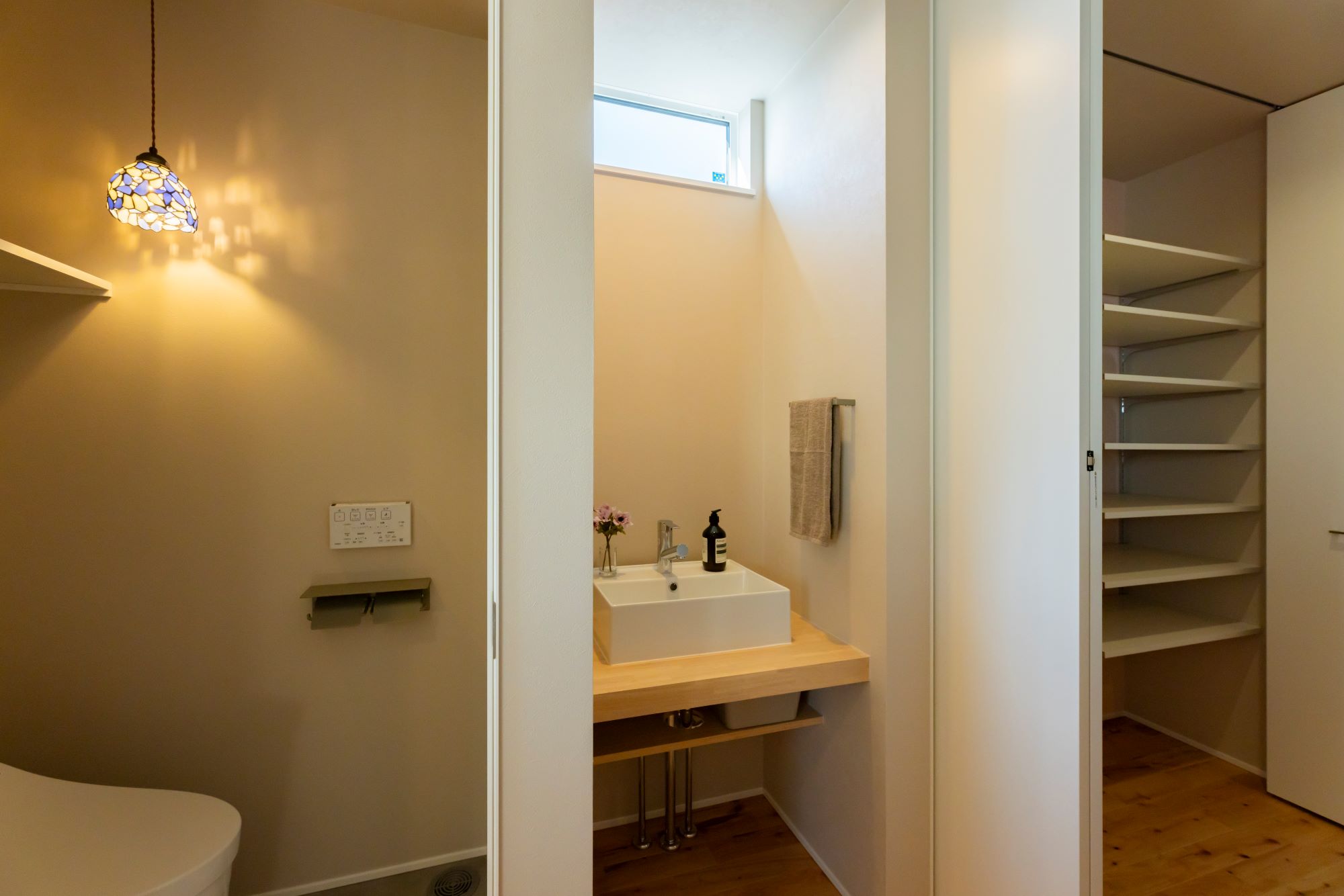 GATE（R+house春日井）｜2階用のトイレは、洗面スペースがコンパクトなデザイン。ナチュラルなライトと洗練された洗面台が調和し、温かみのある落ち着いた雰囲気を演出している。洗面台の隣には収納スペースも確保され、使い勝手が良い。