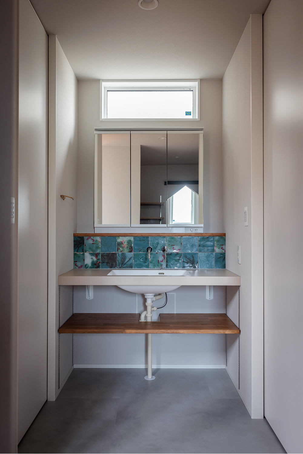 tact design firm【デザイン住宅、子育て、間取り】大きな鏡とモザイクタイルが特徴の洗面スペース。窓から自然光が差し込み、明るい雰囲気に