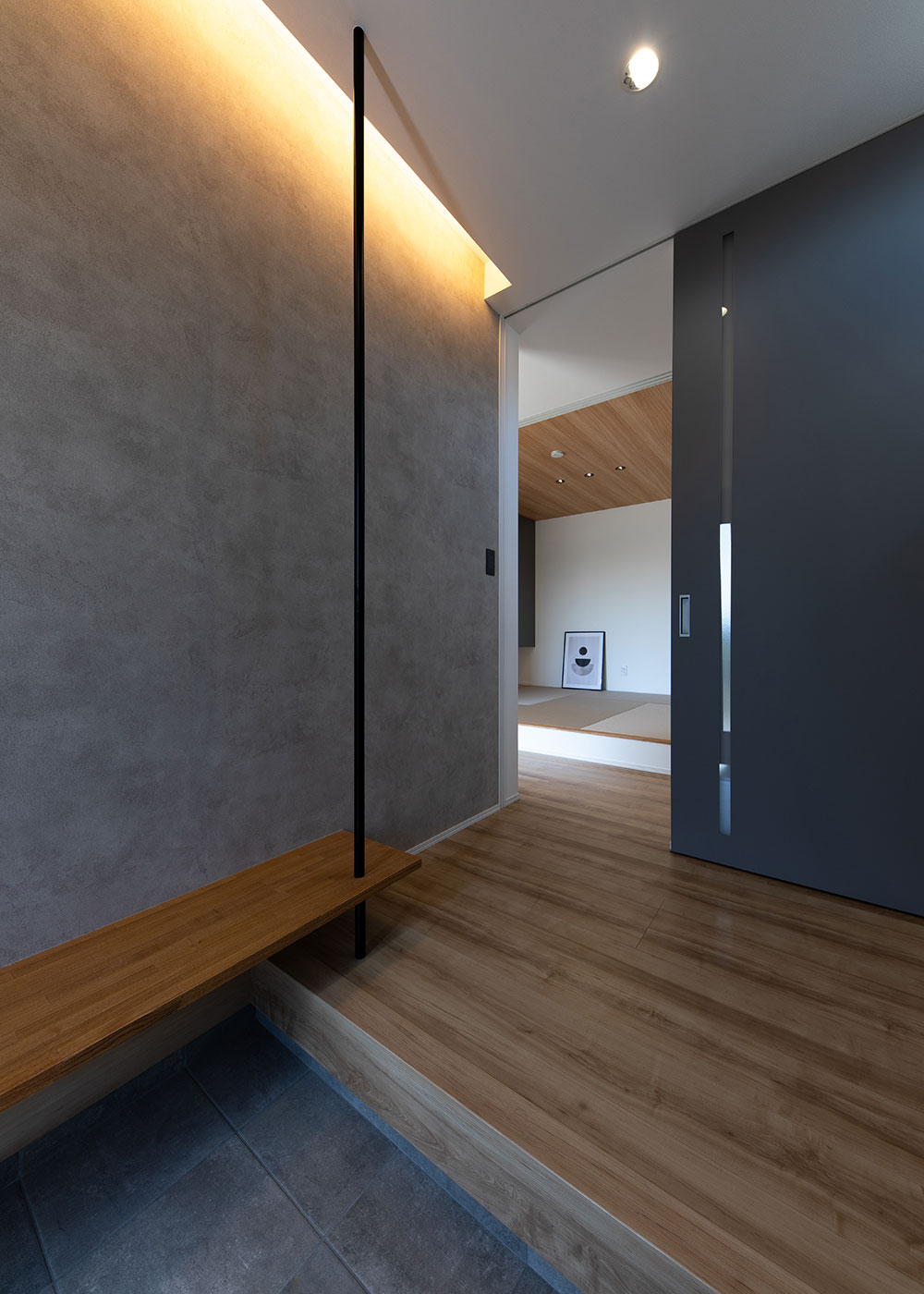 KUREKEN HAUS（榑林建設）【デザイン住宅、収納力、ペット】玄関ホールにも、優しい光を放つ間接照明を。来客の腰掛けにも重宝するベンチは、アイアンポールをアクセントにしたスタイリッシュな仕上げ