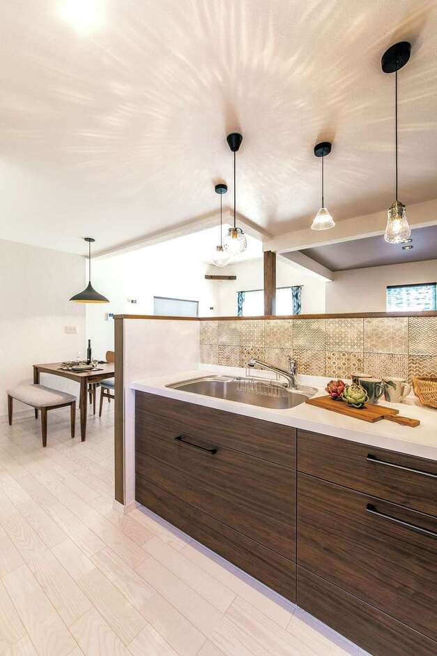 キッチンは顔は見えて手元は隠せるハイカウンター仕様。内側のタイルは落ち着いた色の柄違いを並べて大人っぽく