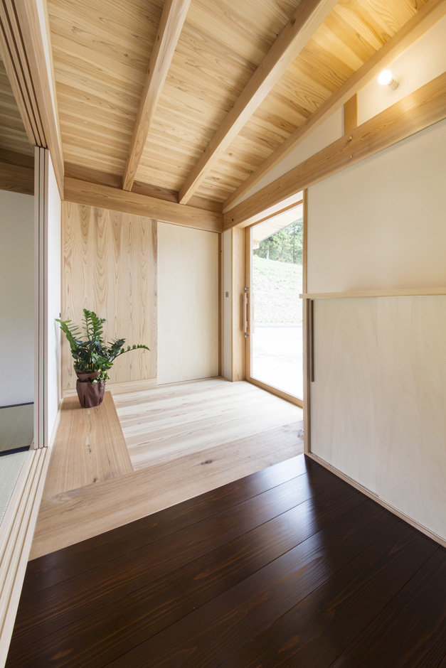 石牧建築【収納力、自然素材、建築家】玄関の土間部分は無垢の杉板。ここまでが土足で、木地になる栗の木のラインで靴を脱ぐ。段差はない。ガラスの玄関扉を採用したことで明るさも十分確保した