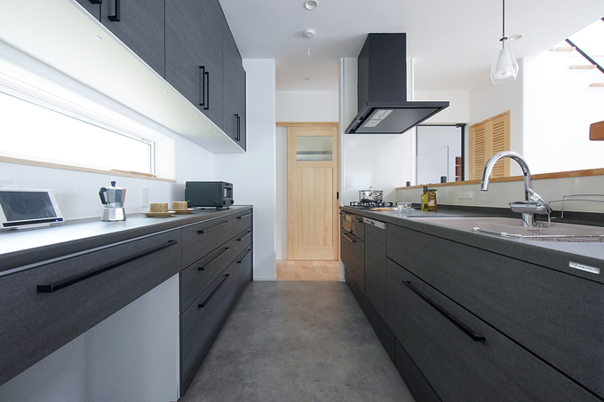 キッチンからパントリー、洗面脱衣室へと続く、家事動線を意識した間取り。明るいリビングやダイニングとはうって変わって、キッチンに黒を多めに取り入れることで空間を引き締めている