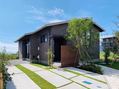 平屋特有の大屋根が印象的な佇まいの外観。外壁に使用されているタイルはこだわりの逸品で、一枚一枚の彩りある表情が外観にありがちな無機質さを打ち消し、温もりのある雰囲気を生み出している。太陽光発電が屋根一体型で搭載されていることも見逃せない