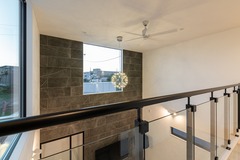 モダンなデザインの渡り廊下。広々とした空間に光が差し込み、アクセントウォールが空間全体に洗練された雰囲気を与えている。