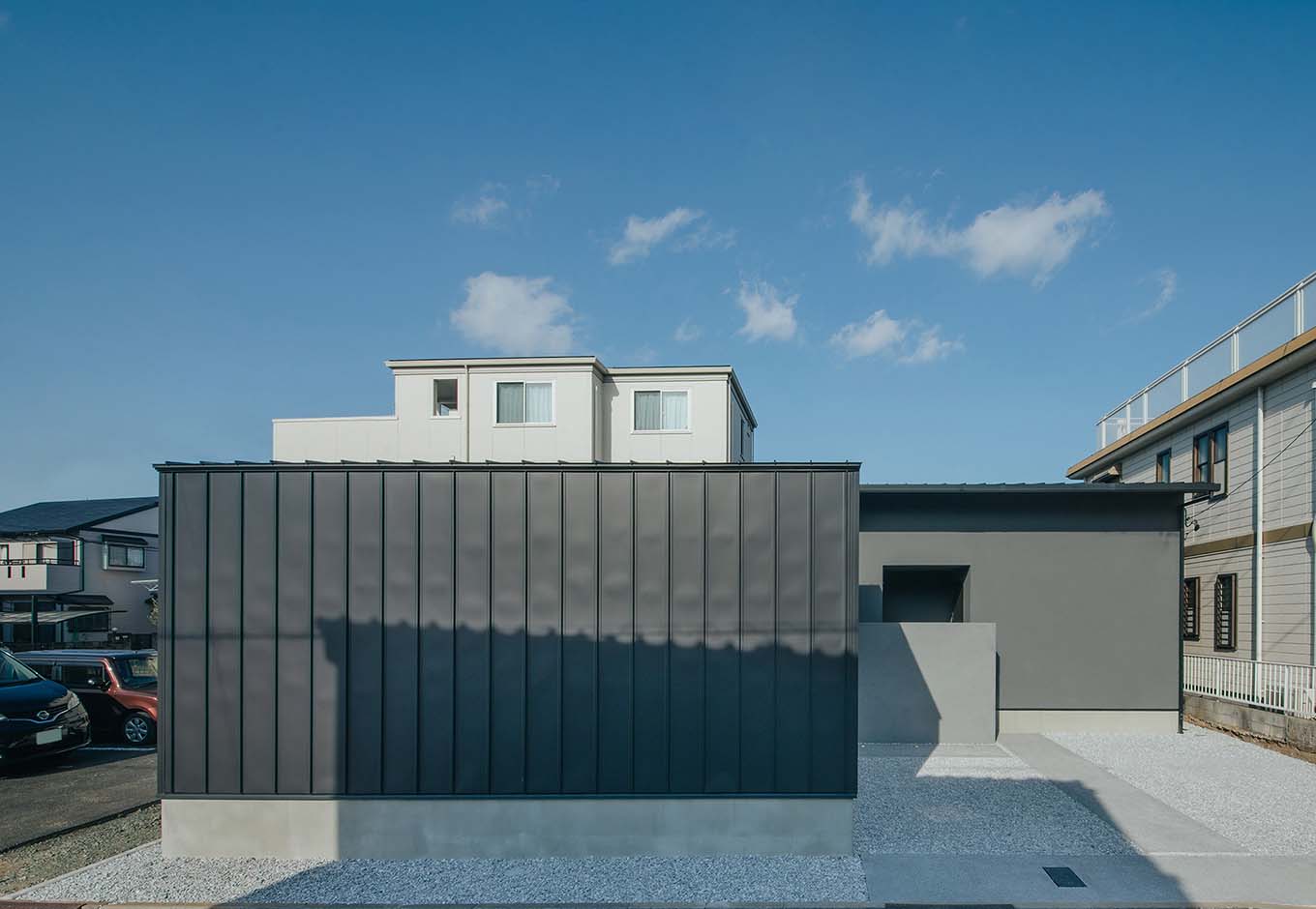 平屋建築ブルーハウス【デザイン住宅、建築家、平屋】手前の壁と奥の壁の素材を変えることで、同じグレートーンでも奥行きのある外観デザインに