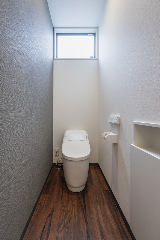 トキワハウス デザイン アンド ビルド（常盤工業）｜シンプルでモダンなトイレ空間。床材は木目調で落ち着きのある雰囲気を演出し、上部の窓から自然光が差し込む。