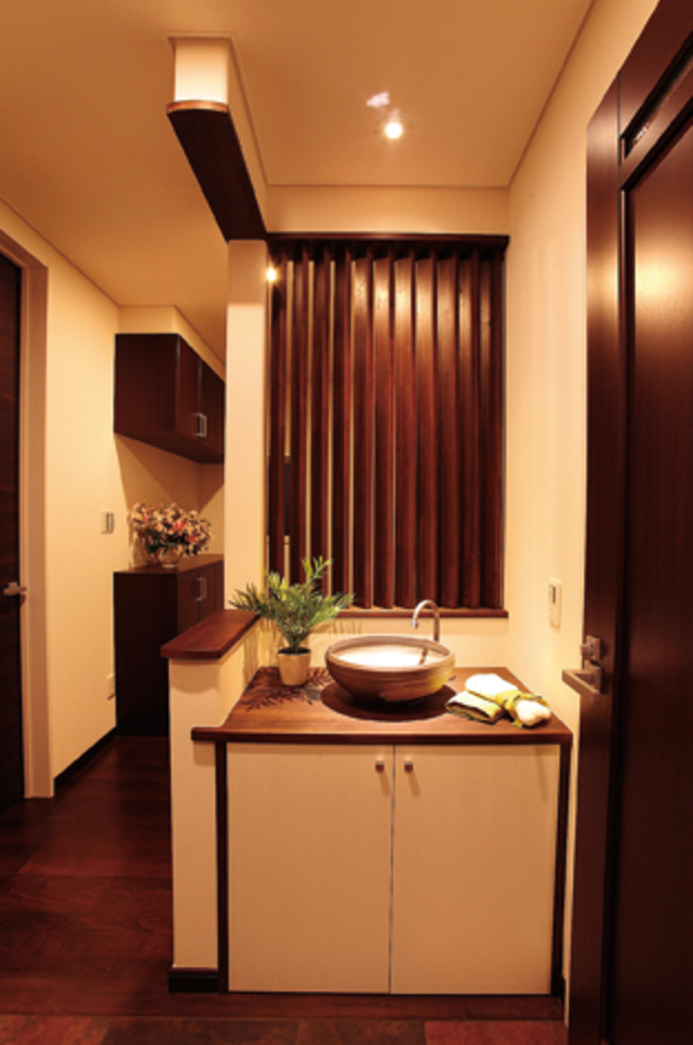 玄関ホールに配された洗面。 斜めの格子が視線を遮りながら光を運ぶ