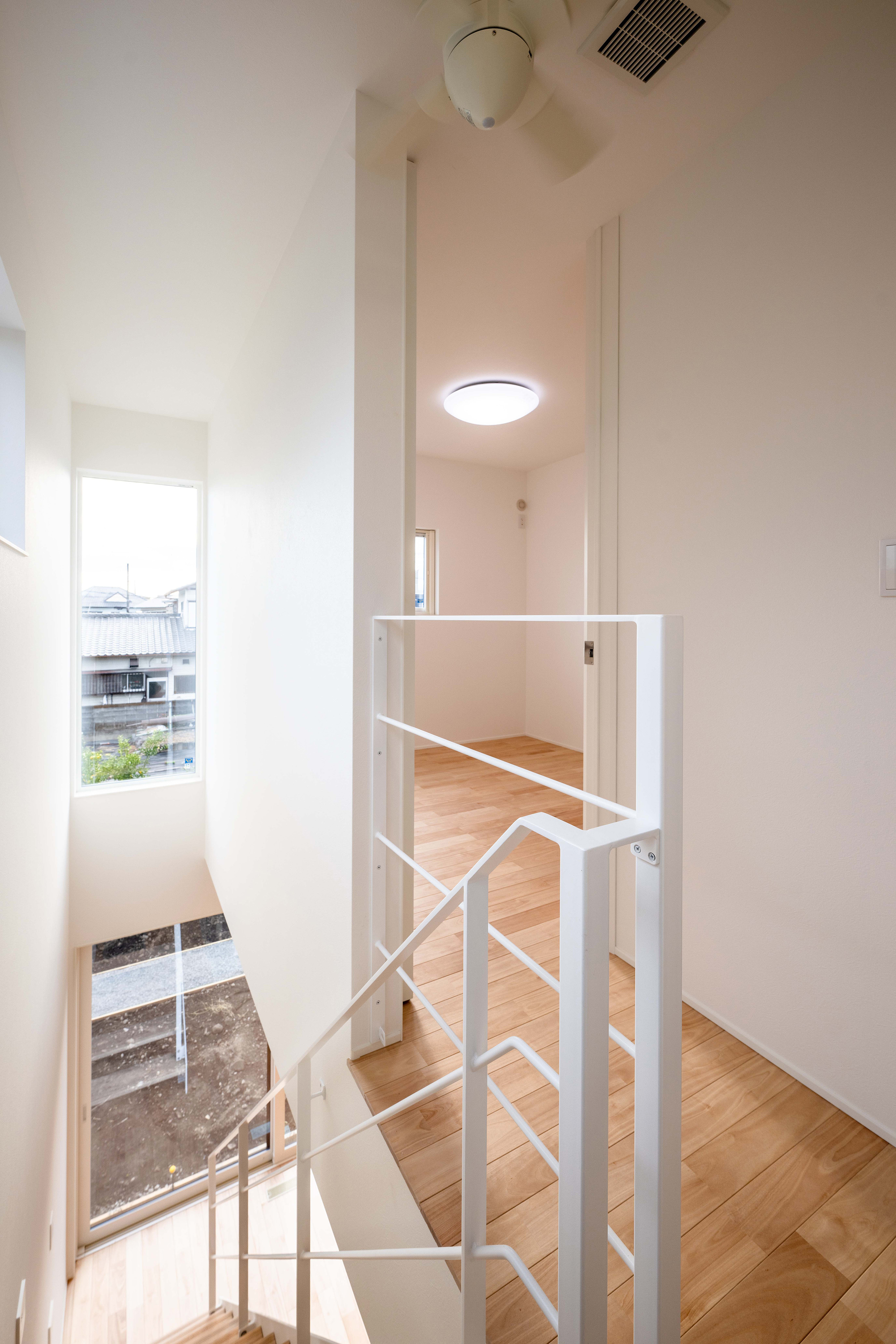 ハウスプラン（R＋house沼津・富士）【デザイン住宅、省エネ、建築家】吹き抜けを通じて、明るさと開放感が1階へと運ばれる。アイアンの階段をブラックにしてアクセントにするケースもあるが、K邸では空間に馴染むホワイトが選ばれた