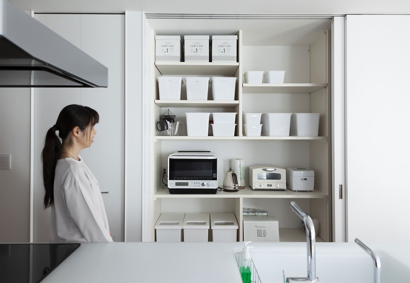 S.CONNECT（エスコネクト）【収納力、趣味、建築家】キッチンの背面に設けた収納スペースは奥さまのこだわりで収納ボックスや家電もすべて白で統一。大きな扉で生活感を隠しておくこともできる