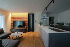 木のぬくもりと質感を楽しみながら暮らせるCOOL＆モダンなLDK。テレビ背面のレッドシダーとブルーのハイドアがグレージュな空間のアクセントに