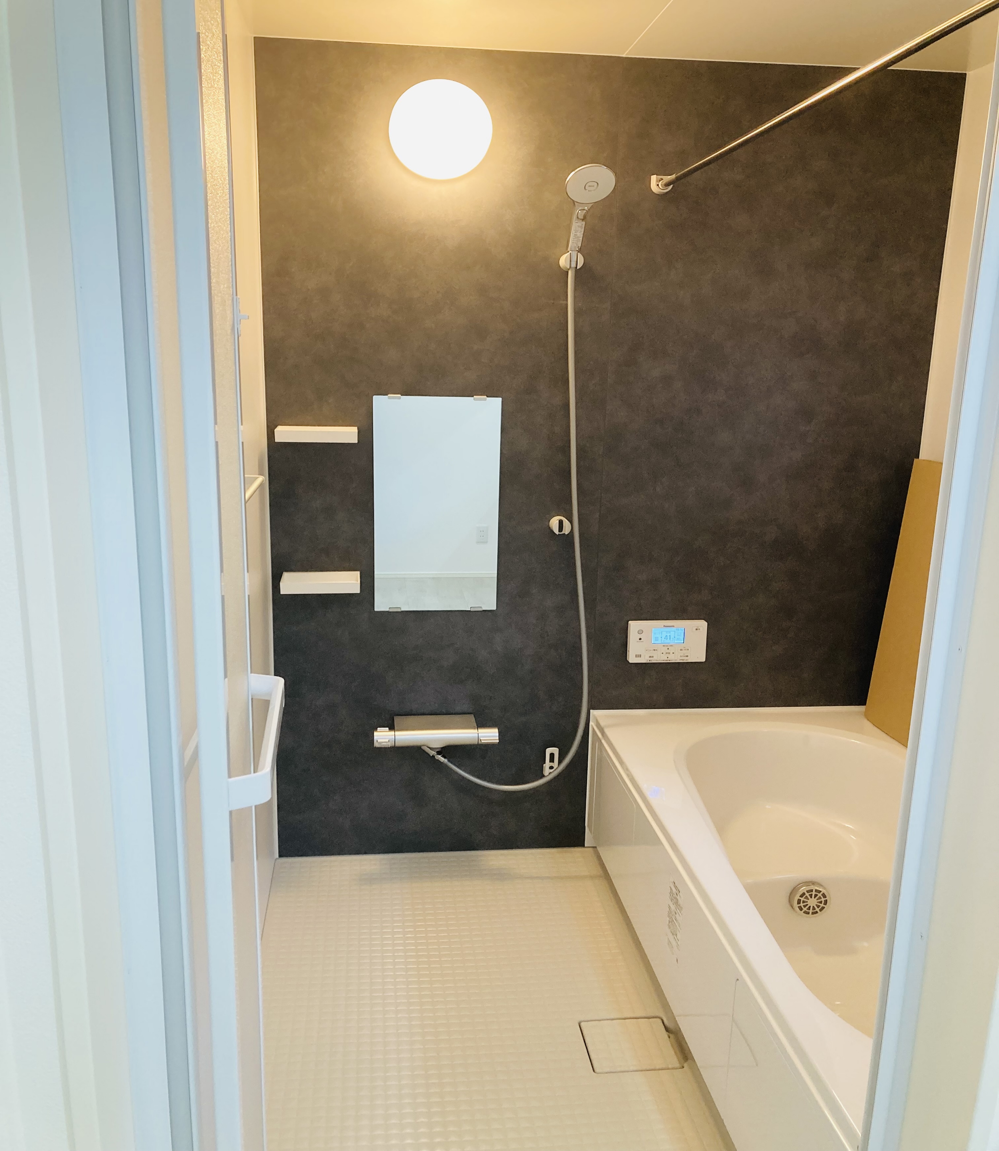 沢田建設｜落ち着いた色調の壁が特徴的なバスルーム。広々とした浴槽とシンプルなデザインが、毎日のバスタイムを快適に演出する。