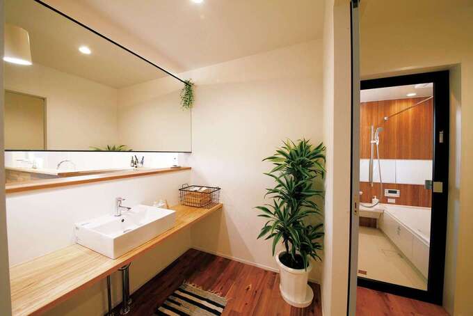 大きな鏡と木目調の浴室でホテルライクに仕上げられた水回りのプラン例。キッチンから近く、家事のしやすさにも配慮が行き届く