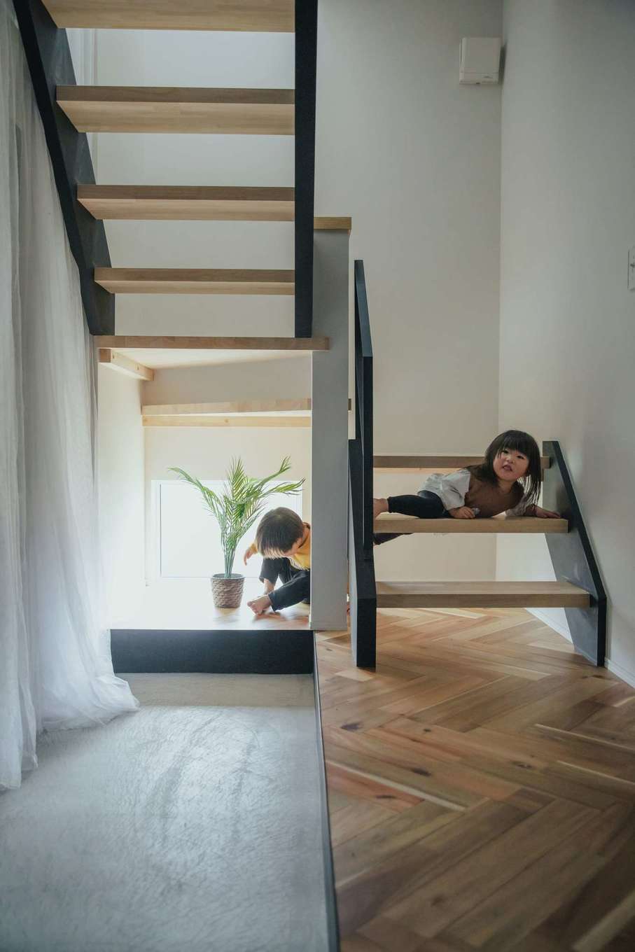 絆家（きずなや）【デザイン住宅、趣味、ガレージ】シューズクローク付きの玄関。ホールの床はヘリンボーンに仕上げ、スケルトン階段の下には地窓を設置