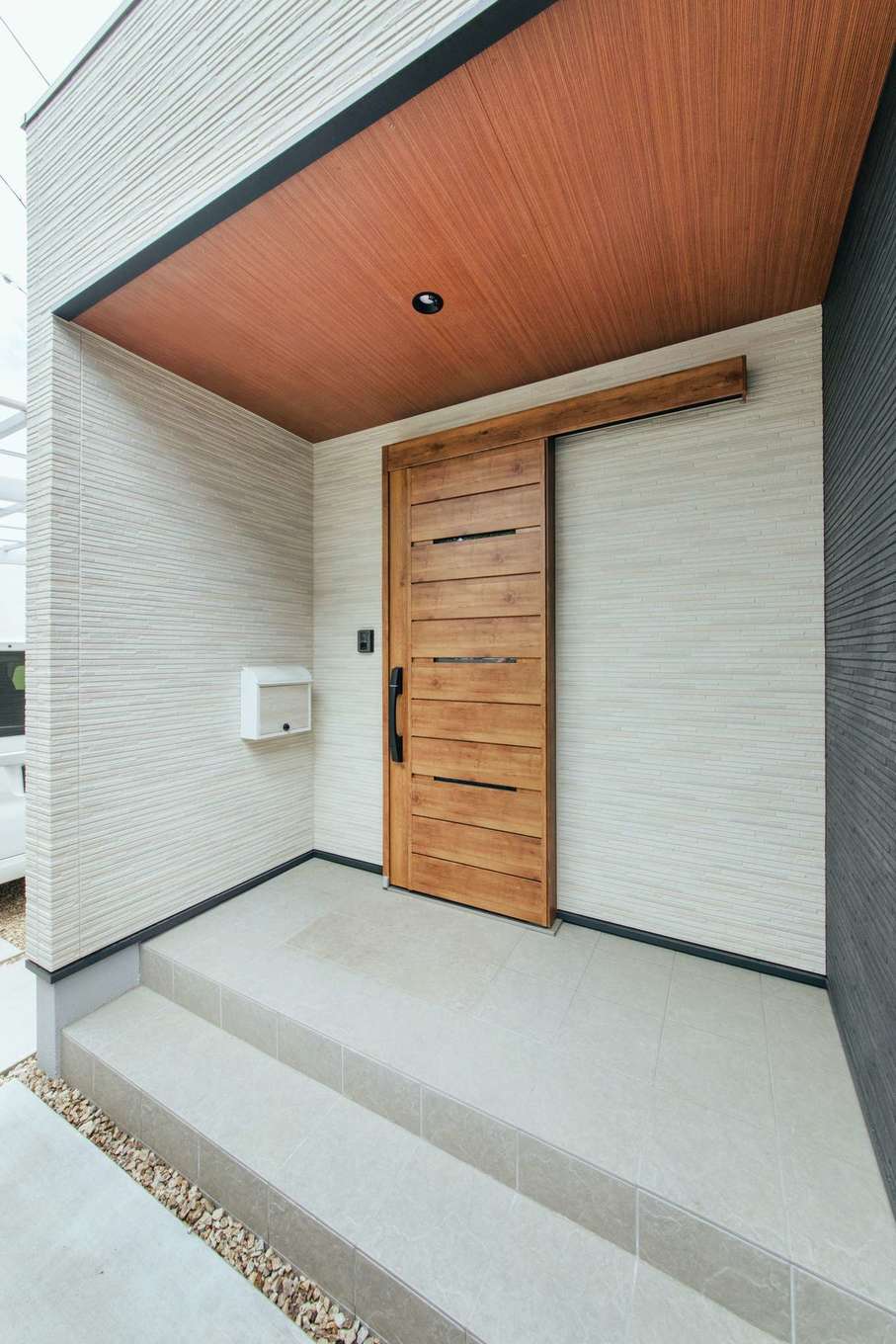 子育て安心住宅 Design Craft Office【デザイン住宅、趣味、平屋】建物の東側に配置した住居用の玄関。広めに設けた屋根付きポーチにも鉢植えを飾ることができる