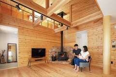 無垢材を惜しみなく使った室内は、アウトドア好きな夫婦にぴったりの山小屋をイメージ。8寸の大黒柱はヒノキのみがき丸太、床は天竜杉、梁はオクシズ（奥静岡）材、壁はパイン材。大屋根を採用したことで吹抜けと小屋裏が生まれ、平屋とは思えないほどの開放感がある