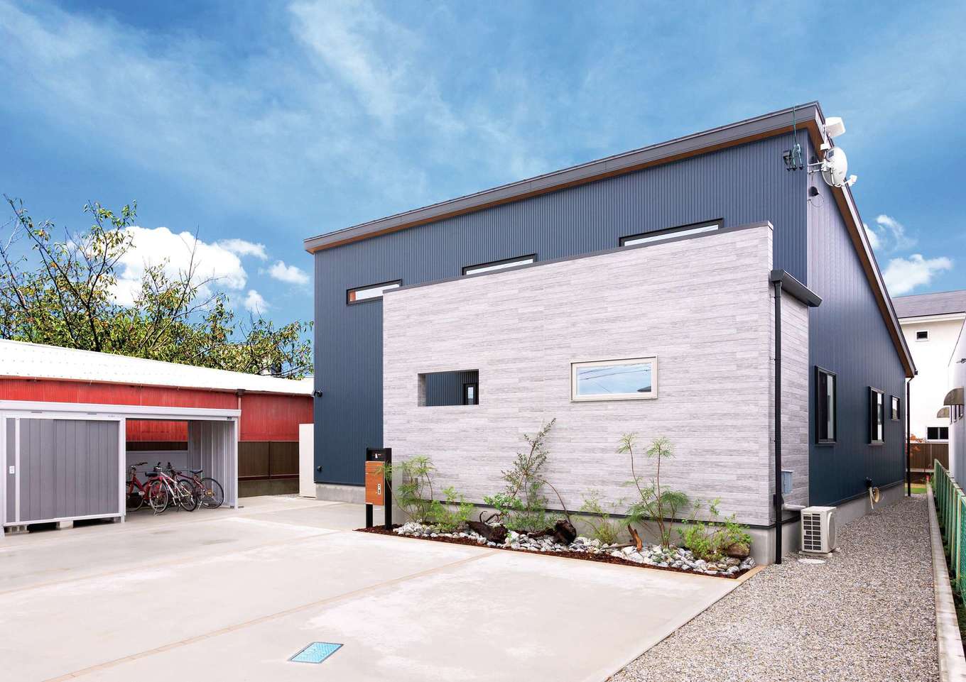 Yamaguchi Design 【省エネ、間取り、平屋】一見、平屋とは思えないほどのスケール感がある外観。交通量の多い北面道路を考慮して、グレーのガルバリウムにサイディングを組み合わせ、ポーチと玄関をやわらかく目隠しした。片流れの屋根に18kWの太陽光発電を搭載