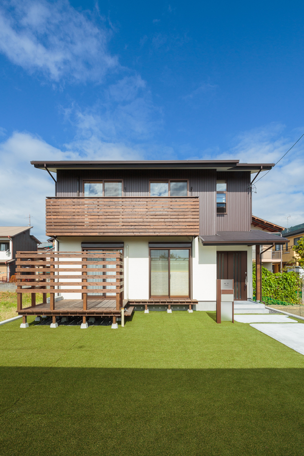 青空と緑の芝生に映える、白と茶の外観。総２階は、構造的にも安定している