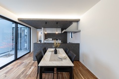 アカシアの無垢床に、グレーで揃えたキッチンの腰壁と下がり天井。仕込まれた調光式の間接照明が、格好いい空間をさらに演出します。