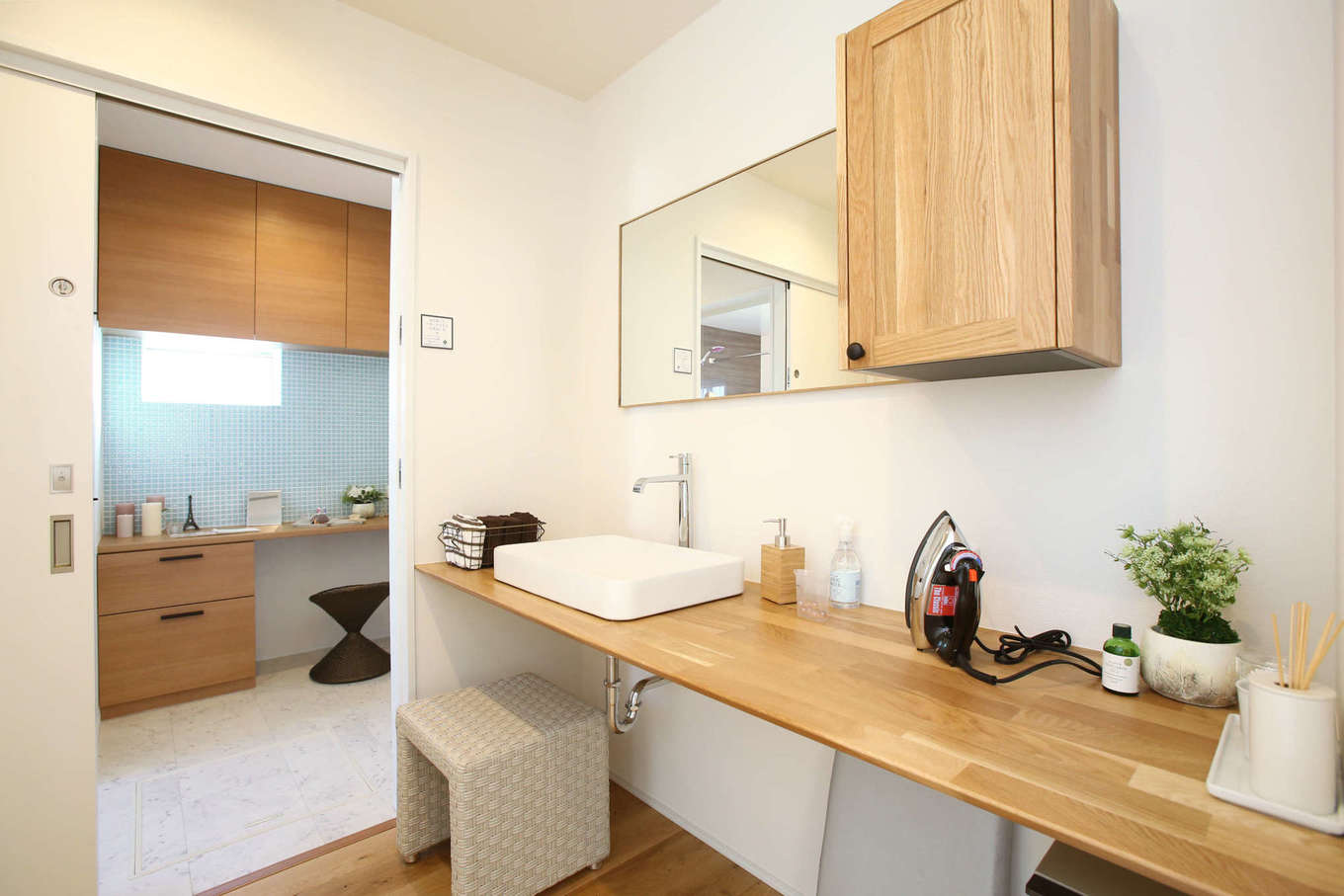 片桐建設【デザイン住宅、間取り、スキップフロア】脱衣室と洗面室を離すことによって、誰かが入浴中でも自由に洗面や歯磨きができる。洗面室はトイレの手洗いコーナーも兼ねていて、アイロンができるほどワイドな棚も造作した