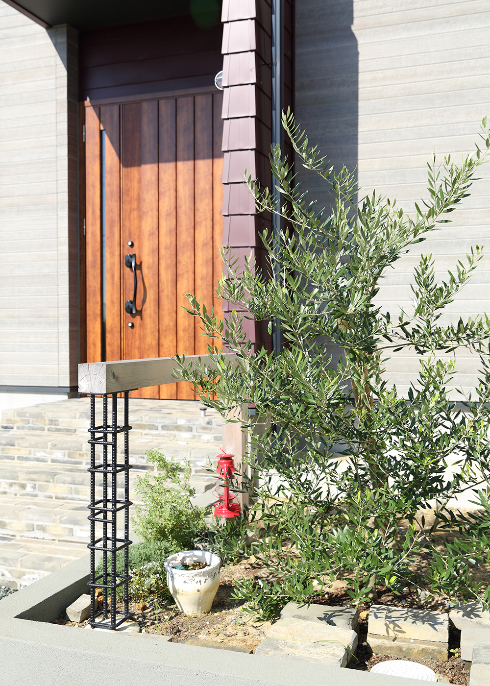 丸昇彦坂建設【デザイン住宅、趣味、インテリア】アンティーク仕上げでモダンな雰囲気も感じる、特徴的なアプローチ。オリーブの木と素材を活かした手摺が見事に調和している