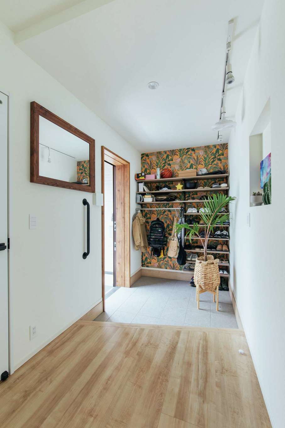 子育て安心住宅 Design Craft Office【デザイン住宅、趣味、平屋】玄関の靴棚の背面には、植物をモチーフにしたアクセントクロスを採用。植物のオブジェやアートを飾るニッチも設け、明るく個性的に演出した